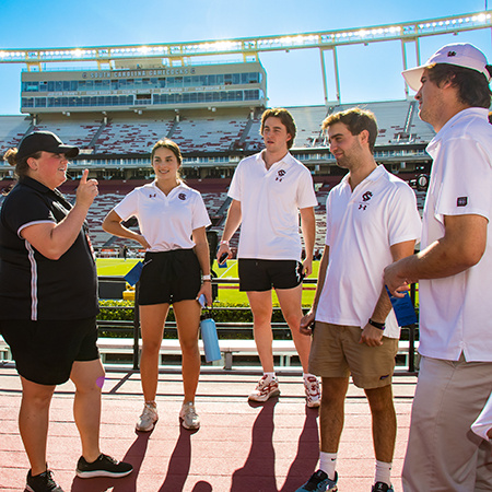 四名体育和娱乐管理专业的学生在橄榄球比赛前听取南加州大学体育系一名成员的指示。bob体育苹果版下载