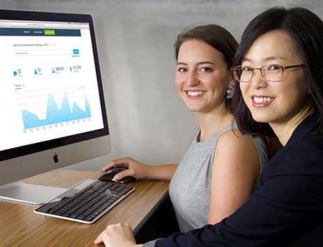 一名学生和一名教职员工与一台演示锁眼平台的电脑合影