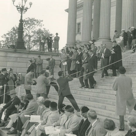 人们聚集在南卡罗来纳州议会大厦的台阶上的黑白照片。前排的人坐在较低的台阶上。在背景中，一群人走下台阶，人们拿着相机从下面拍摄他们。