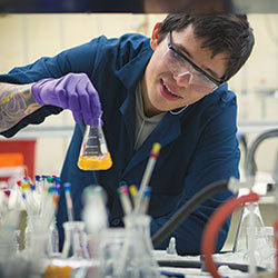 学生在实验室的工作台上旋转烧杯里的黄色液体。