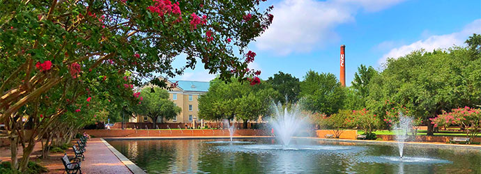 三个喷泉在一个反射池周围的长凳，与校园和USC的大烟囱的背景。