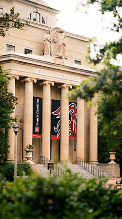 麦基西奇博物馆坐落在历史性的马蹄形建筑的顶部，有大型圆柱和南卡罗莱纳大学的旗帜。bob官方体育登陆