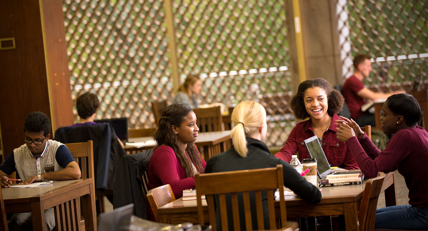 一群学生在图书馆的一张桌子旁一起学习。