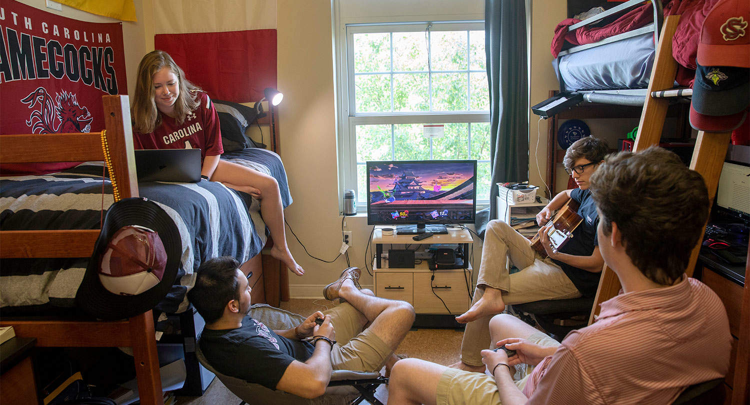 闲逛在休息大厅的四名学生播放视频游戏和吉他。