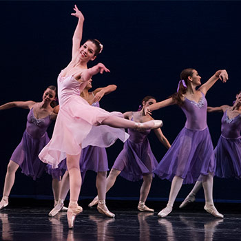 学生们穿着戏服和芭蕾舞鞋在舞台上跳舞。