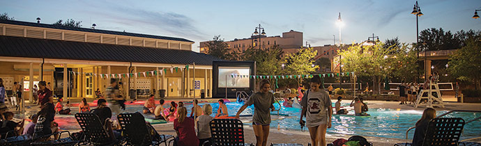 傍晚健身中心的室外游泳池，人们在外面闲逛，准备在潜水电影活动上看电影。