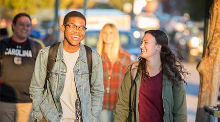当他们走在城市街道时，两个学生互相笑。