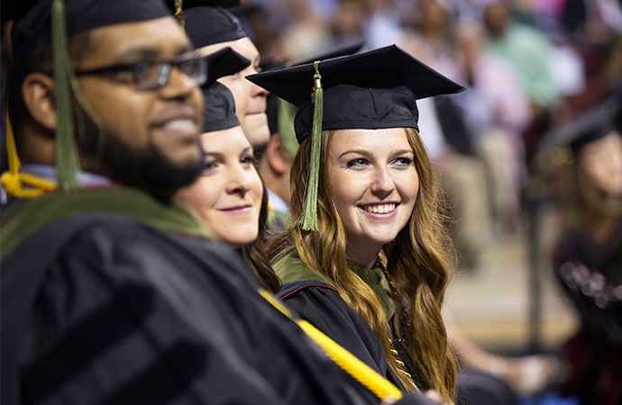 在毕业典礼上，学生们穿着毕业长袍，戴着毕业帽，一排一排地坐着。
