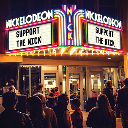 Nickelodeon剧院的发光品牌，上面有文字Nickelodeon，支撑着刻痕，人们聚集在前面。