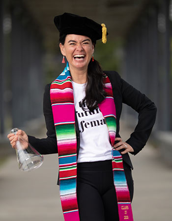 戴安娜洛杉矶佩带的毕业盖帽和长袍的画象拿着烧杯。