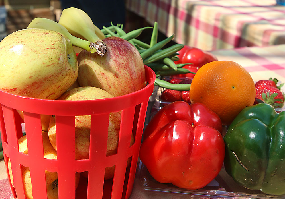 桌上放着一篮子水果和蔬菜。