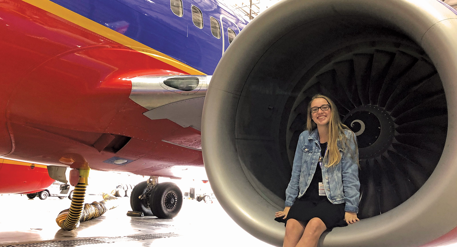 梅根·加拉格尔(Megan Gallagher)坐在西南航空(Southwest Airlines)一架停在机库中的飞机的助推器发动机上。