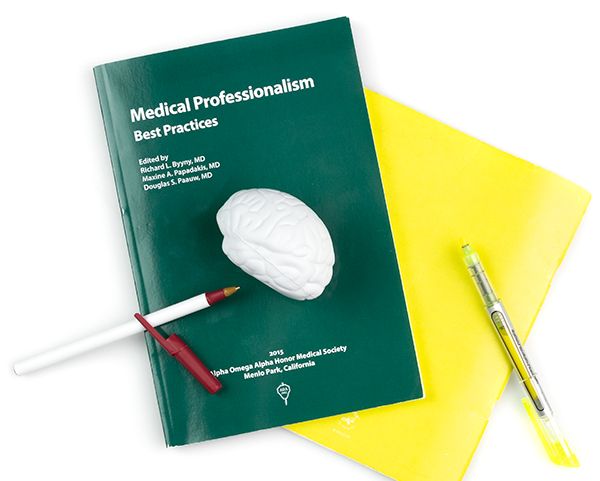 一本名为《医疗专业最佳实践》的书，里面有笔记本、笔和大脑压力球。