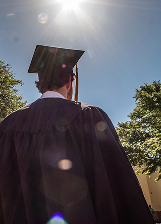 后面的学生戴着毕业帽，身穿蓝色天空背景的毕业服。