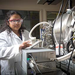 一个深色头发，穿着白色实验服的学生在实验室里工作。
