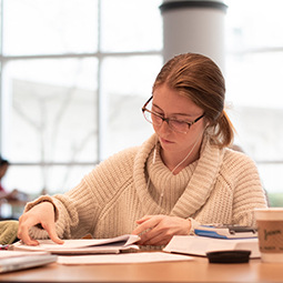 一名女学生戴着耳机在桌子旁工作