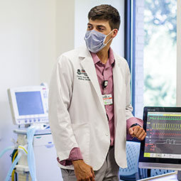 一名穿白大褂的男医学生在模拟实验室检查病人监视器。