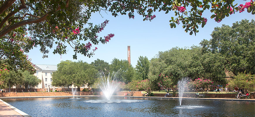 阳光明媚的日子里，南加州大学的大烟囱从托马斯·库珀图书馆的喷泉上方升起