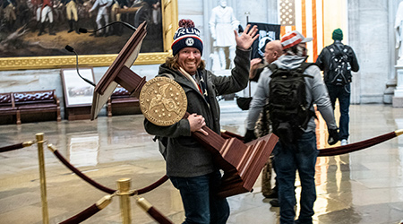1月6日，美国国会大厦发生暴乱，一名抗议者举着讲台对着镜头挥手。