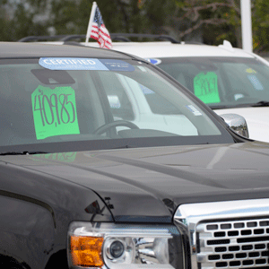 一辆在销售场上的汽车，挡风玻璃上贴着绿色价格标签，背景是其他汽车。