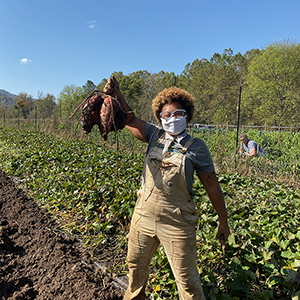 可持续发展卡罗莱纳花园经理萨迪亚·波拉德(sadia Pollard)举起从花园收获的蔬菜