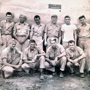 在一张二战档案照片中，十名士兵在一架飞机旁摆姿势。