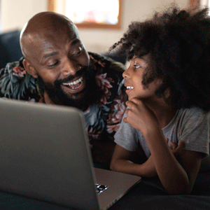父亲和女儿在笔记本电脑上看电影