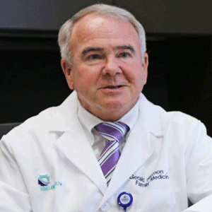 杰拉德·哈蒙医生的照片，穿着医疗外套，打着紫色条纹领带
