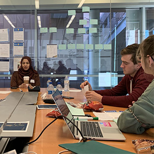 作为课程的一部分，三名国际商科学生坐在桌前，用笔记本电脑工作