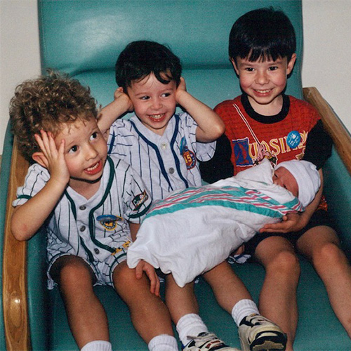 三个年轻的男孩抱着一个婴儿