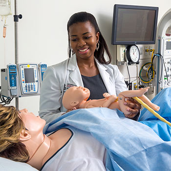 学生拿着医疗实践婴儿与另一个练习病人作为母亲。