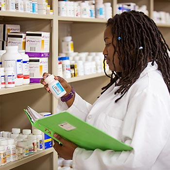 药剂学学生站在药柜前阅读药瓶上的标签。
