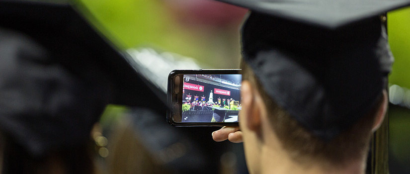 毕业时手持照相手机的学生