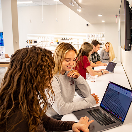 在Gamecock的iHub商店里，学生们一边看着笔记本电脑，一边与销售代表交谈。