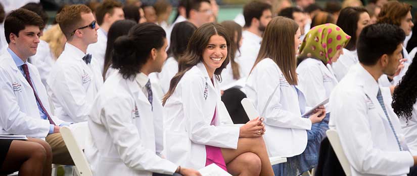 地中海女学生坐在行与其他学生在户外仪式