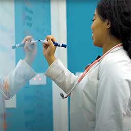 女医科学生在反光白板上写字。