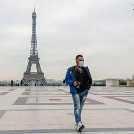 一名男子戴着面罩走在巴黎街头，背景是埃菲尔铁塔
