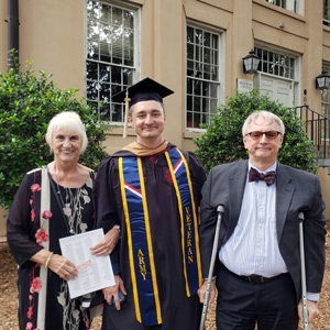威廉·布朗头戴毕业帽，身穿毕业礼服，与父母站在一起