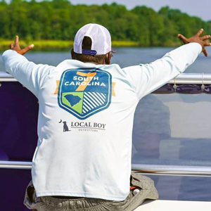 一名男子戴着棒球帽，穿着印有南卡罗来纳字样的t恤，坐在库珀河上的一艘船上